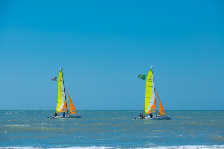 a group of people flying kites in a body of water