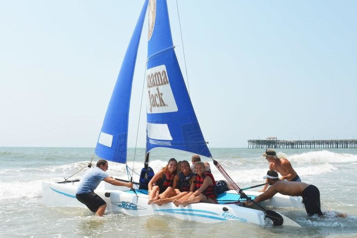 Staff pushing a sailboat ride into ocean in myrtle beach