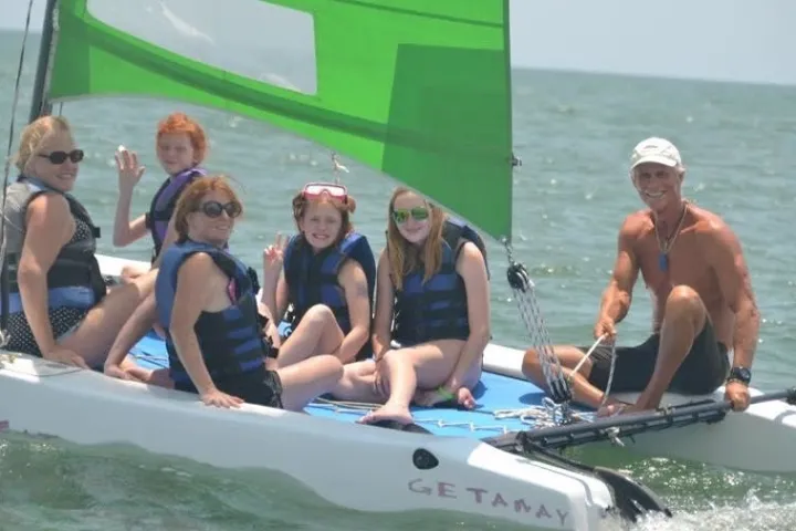 People smiling at the camera on a sailboat ride at downwind sails watersports